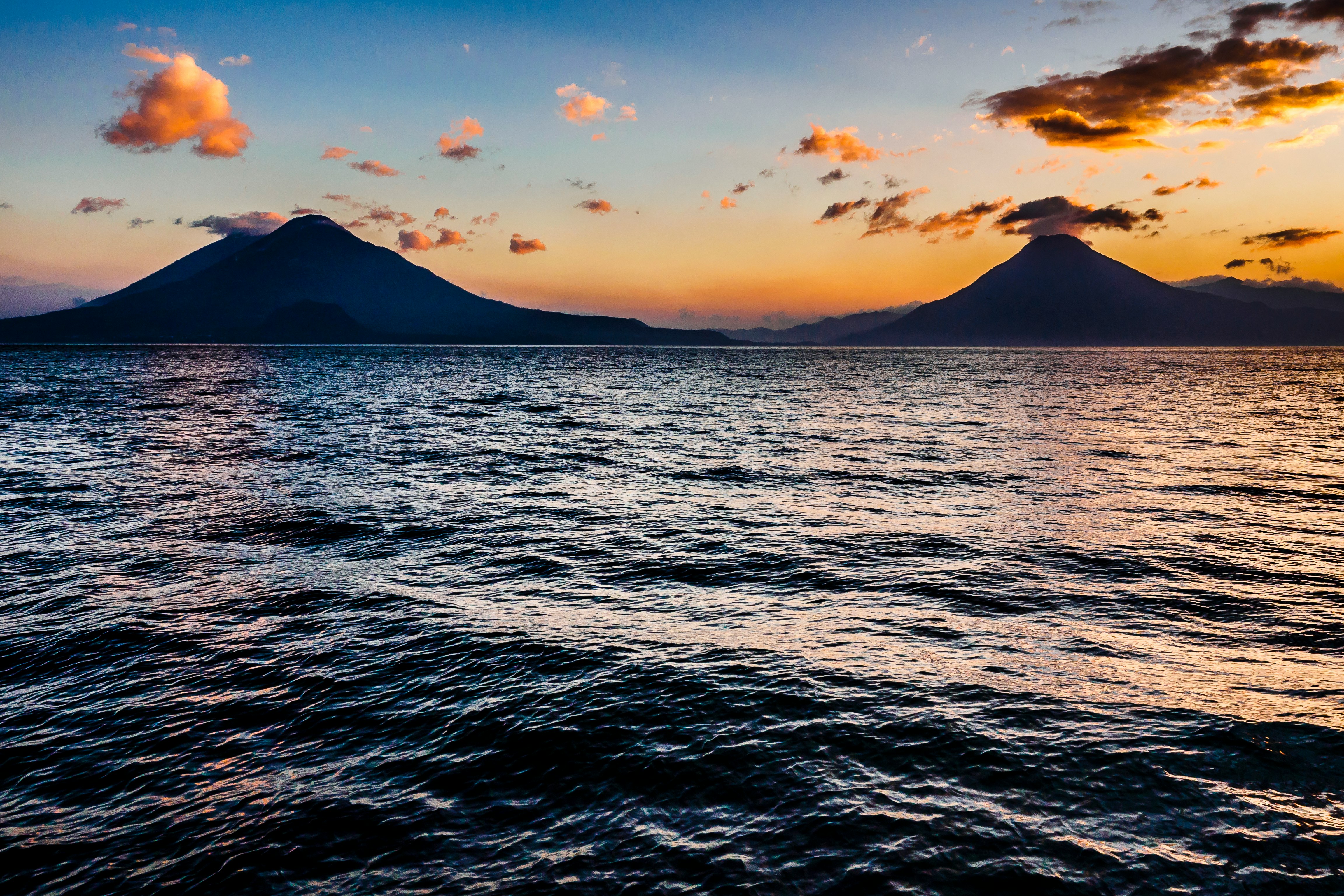 body of water near mountain during sunset